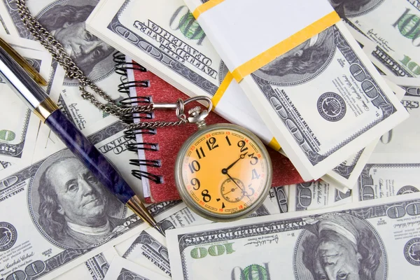 Taschenuhr, Notizbuch und Stift auf einem Stapel Dollars, die Zeit und Zeit reflektieren. — Stockfoto