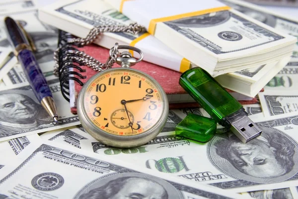 Кишеньковий годинник, блокнот і ручка на стосі доларів — стокове фото