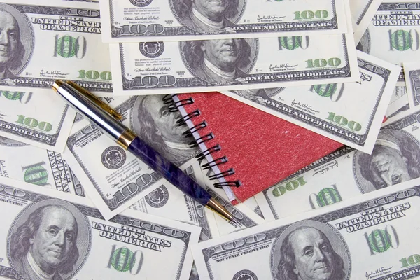 Dollárt, a notebook és a toll, háttérben pénz — Stock Fotó