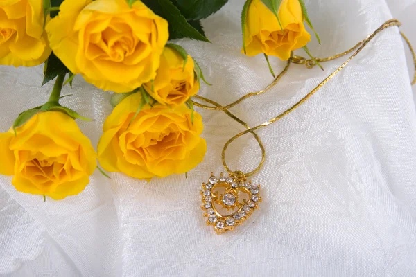 美丽的黄玫瑰和白色的丝绸上的金心 — 图库照片