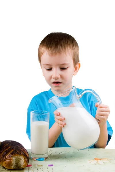 Rapaz com um jarro e um copo de leite — Fotografia de Stock