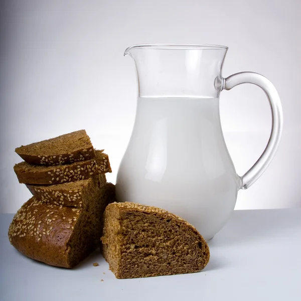 Pão fresco com jarro de leite — Fotografia de Stock