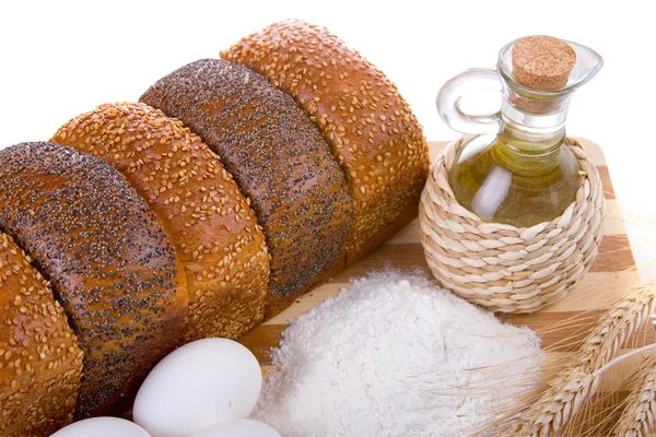 Frisches Brot, Eier, Mehl und Öl auf einem Holzbrett — Stockfoto