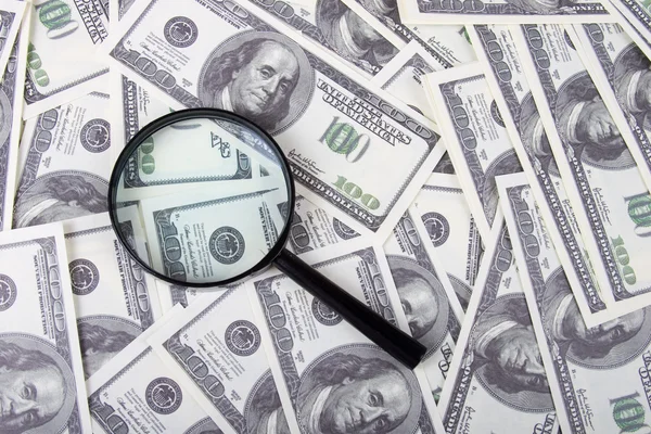 Magnifying glass on a stack of dollars — Stock Photo, Image