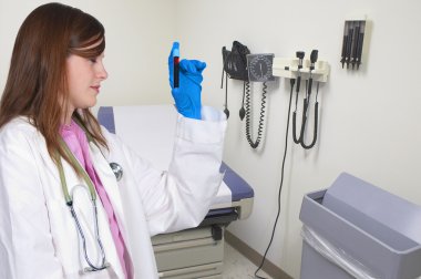 A beautiful young female doctor holding a test tube vial sample of blood clipart