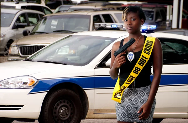 一个年轻貌美的女人 抱着手枪穿警察作为窗扇线磁带 — 图库照片