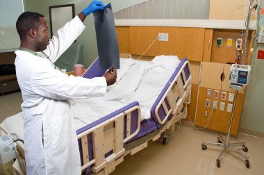 Black African American man radiologist looking at a patients x-ray. clipart