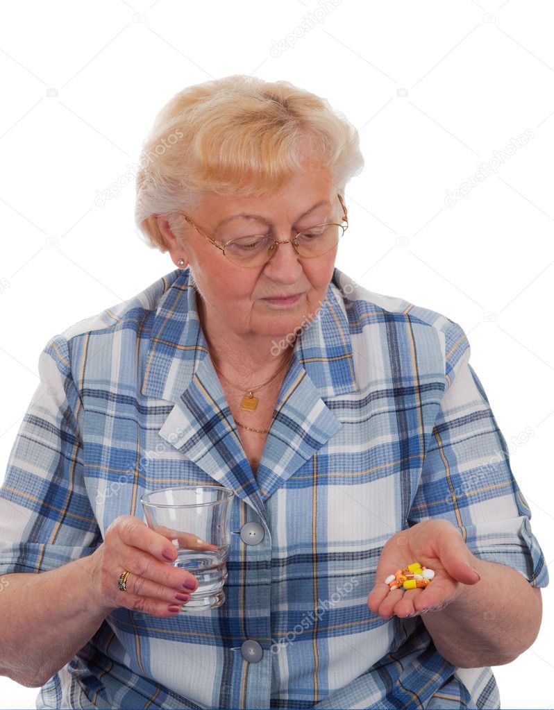Elderly woman looking at her hand with pills - isolated