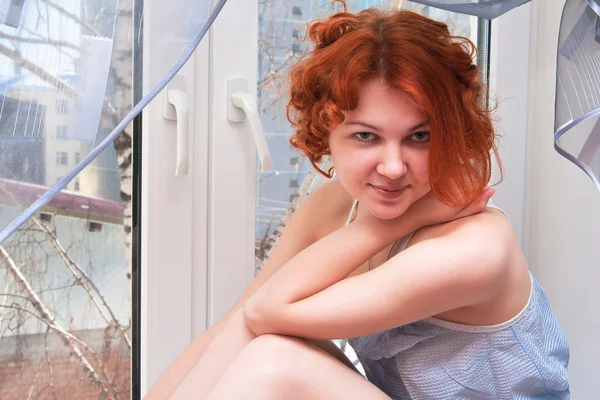 Sexy jonge vrouw zittend op de vensterbank — Stockfoto
