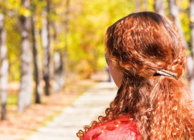 Ginger-haired woman walking in fall forest clipart