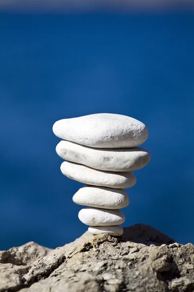 Pebbles empilhar em rocha e mar borrado — Fotografia de Stock