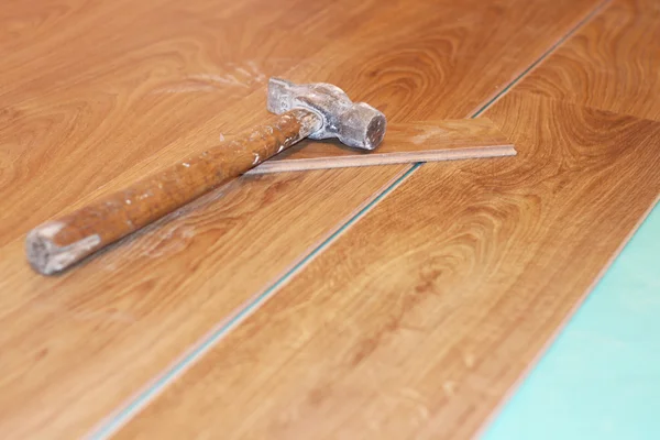 Hammer and laminate plank on floor — Stock Photo, Image