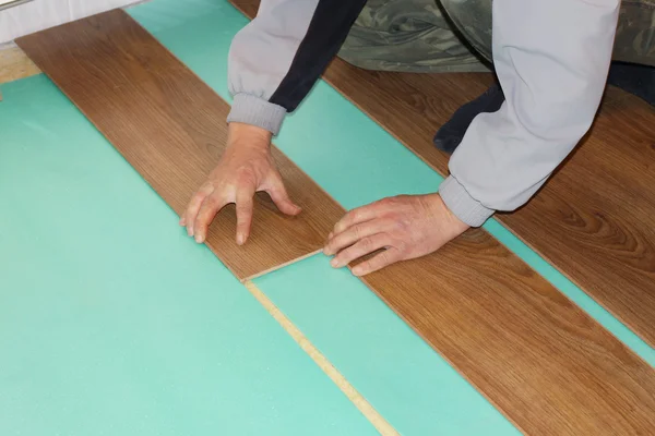 Працівник встановлює нові ламіновані підлоги — стокове фото