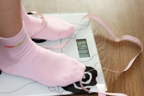Kvinna i skala med rosa måttband, kost — Stockfoto