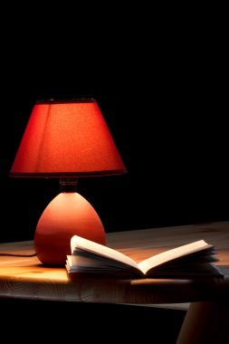 ahşap masa üzerine bir kitap aydınlatıcı lamba