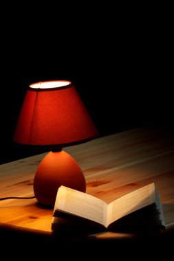 ahşap masa üzerine bir kitap aydınlatıcı lamba