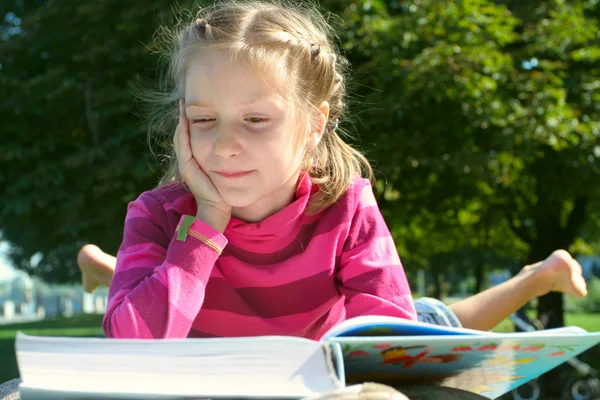 Dítě dívka čtení v parku — Stock fotografie