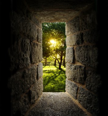 Sunrise through trees as viewed out of a castle-like stone windo clipart