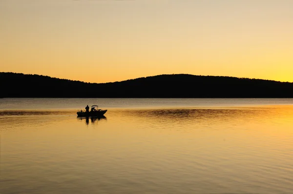 stock image Early morning fishing boat on a lake at dawn