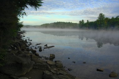 Mist rising from a lake in the wilderness clipart