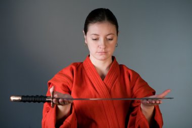 bir samuray kılıcı ile kırmızı bir kimono içinde bir genç kız