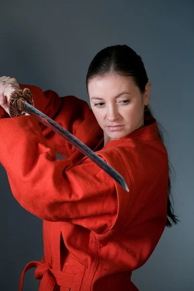 stock image A young girl in a red kimono with a samurai sword