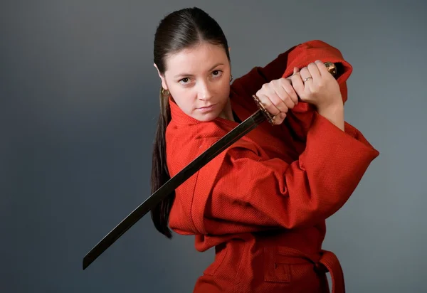 stock image A young girl in a red kimono with a samurai sword