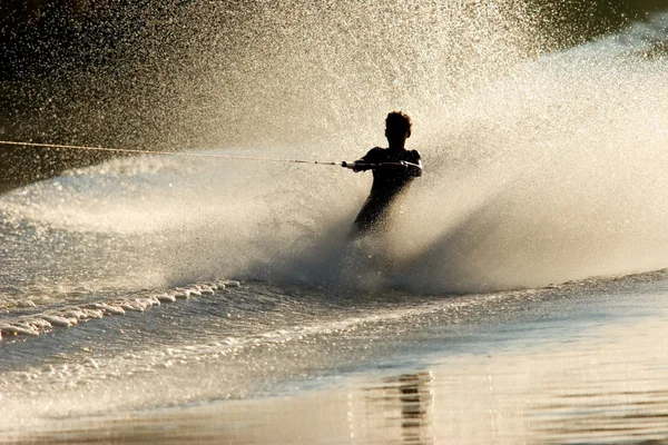 バックライト付きの水スプレーで裸足水スキーヤーのシルエット — ストック写真