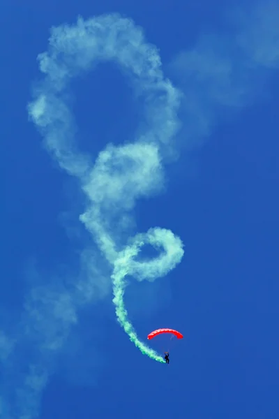 曲技飛行ショーの間の煙道でループ状の下降を行うパラシュート — ストック写真