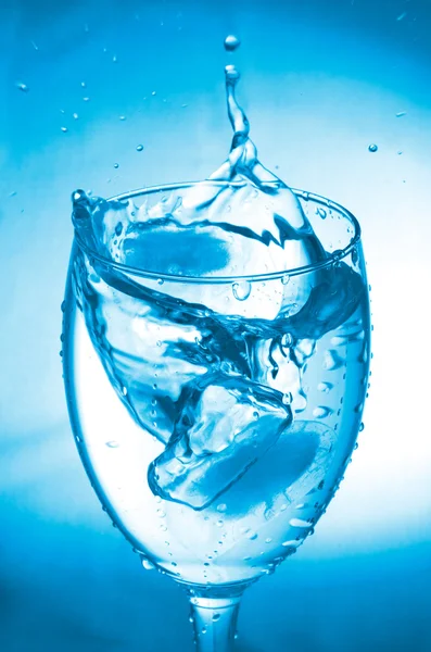 Glas met splash op blauwe achtergrond — Stockfoto