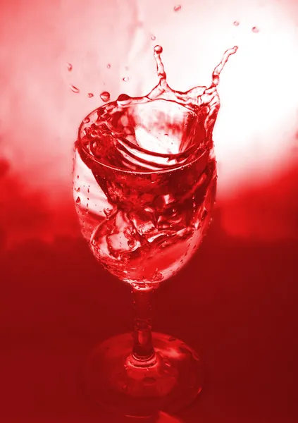 Glas mit Spritzer auf rotem Hintergrund — Stockfoto