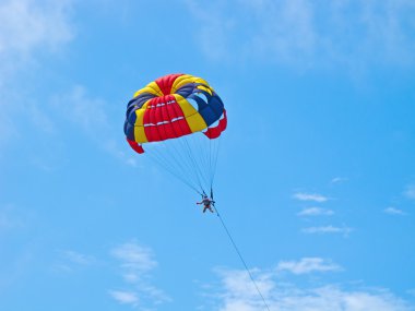 Parasailing in the deeep blue sky clipart