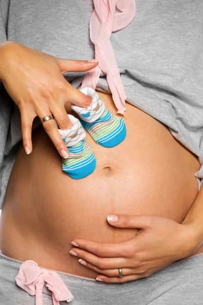 Pregnant woman holding pair of shoes for baby girl — Stock Photo, Image