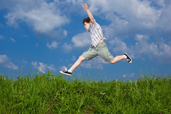 Мальчик Прыгает Зеленому Лугу Фоне Голубого Неба — стоковое фото