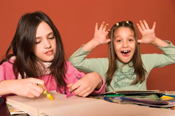 Girl drawing and cheeky girl in classroom — Stock Photo, Image