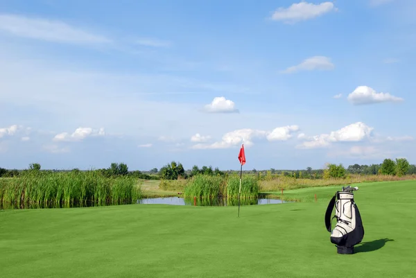 Campo de golfe com bandeira vermelha e saco — Fotografia de Stock