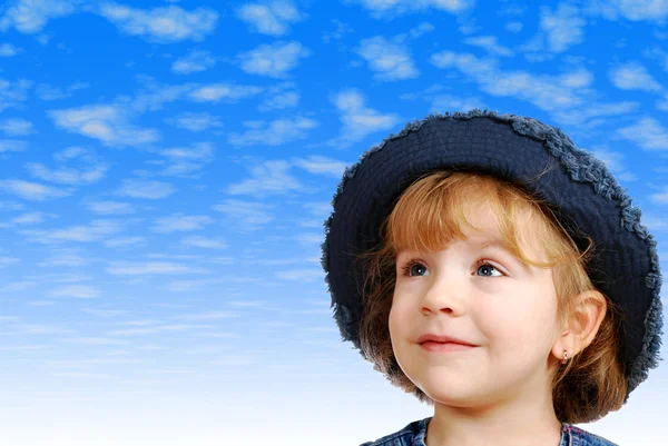 牛仔裤的帽子和蓝色天空背后的小女孩 — 图库照片