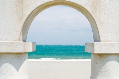 Looking at the ocean through arch door clipart