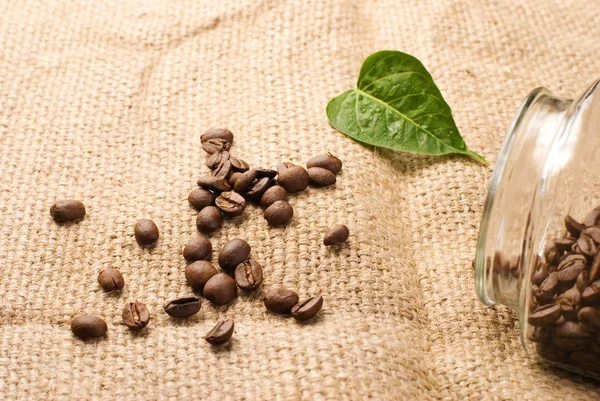 Kávová zrna do sklenic na hnědé pytloviny — Stock fotografie