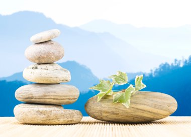 Stack pebbles in front of mountains with light morning fog clipart