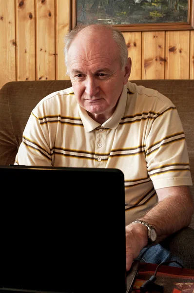 Senior man is working on laptop in living-room — Stock Photo, Image
