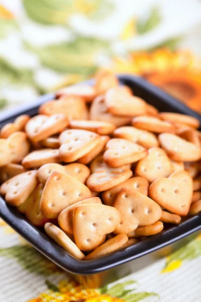 Salted heart shaped crackers in black bowl — Stock Photo, Image