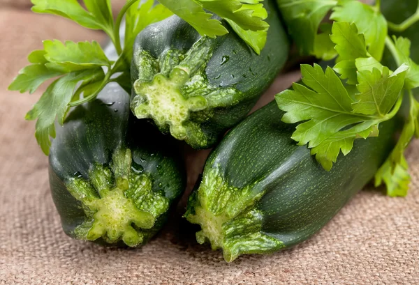 stock image Green zucchini with parsley on a rough sackcloth