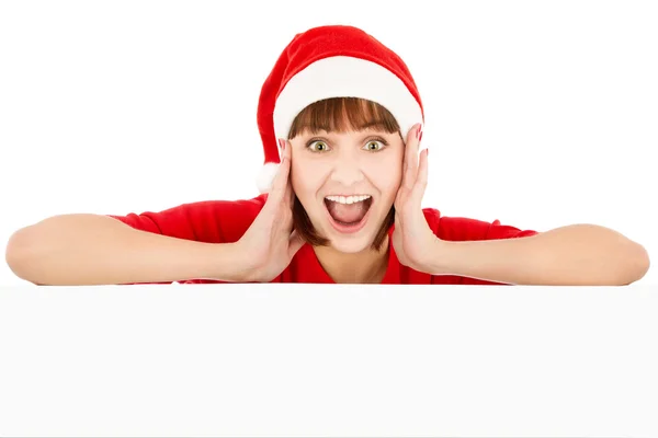 Donna sorpresa in cappello rosso Santa appoggiato su cartellone bianco — Foto Stock