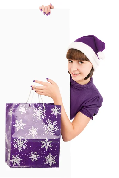 Woman with shopping bag in Santa hat holding blank billboard — Stock Photo, Image