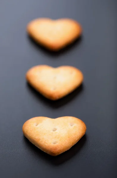 Drei Gesalzene Herzförmige Cracker Auf Schwarzem Hintergrund — Stockfoto