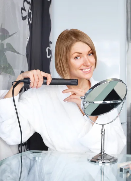 Woman using a hair straightener — Stock Photo, Image