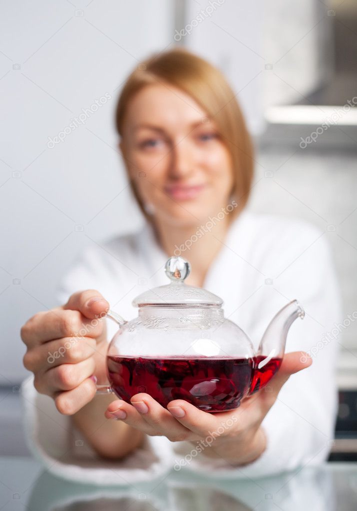 Woman drinking tea (focus of the teapot)