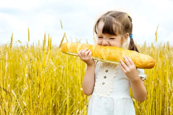 Girl eating a long loaf — Stock Photo, Image