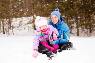 Mutlu aile; genç anne ve kızı kış parkta (odak yer çocuk eğleniyor)